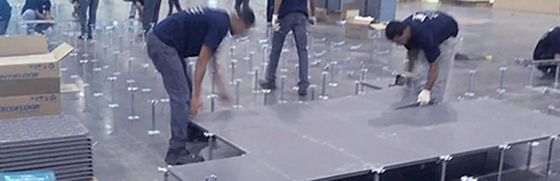 Equipe a instalar placas de piso elevado num salão amplo