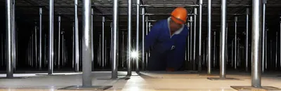 Profissional a trabalhar sob o piso elevado, entre os pedestais